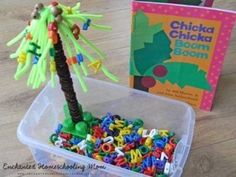 a plastic container filled with letters next to a book and a palm tree in front of it