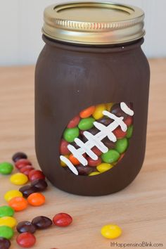 a mason jar filled with chocolate covered candies next to a football design on the lid