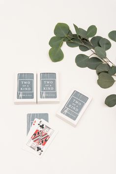 three playing cards sitting on top of each other next to some leaves and a plant