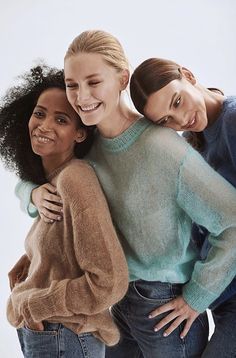 three young women are hugging and smiling for the camera while standing in front of a white background