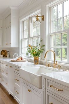 a large kitchen with white cabinets and gold hardware on the countertops, along with an island style sink