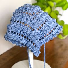 a blue crocheted hat sitting on top of a wooden table next to a potted plant