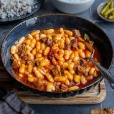 a skillet filled with beans and meat on top of a wooden cutting board next to other dishes