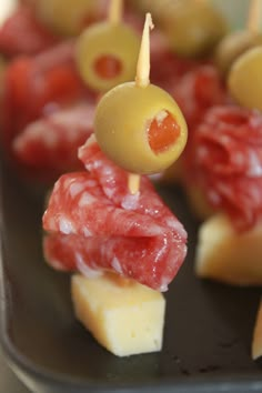 small appetizers with olives, meat and cheese are on a black plate