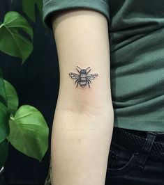 a woman's arm with a small tattoo of a bee on the back of her left arm