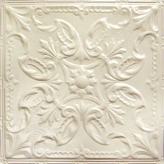 a white square tile with ornate designs on it