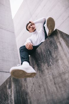 a man sitting on top of a cement wall with his feet up in the air