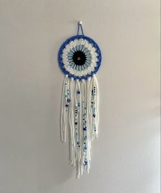 a blue and white dream catcher hanging from the wall with beads on it's side