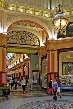 people are walking around in an indoor shopping mall with lights on the ceiling and chandeliers hanging from the ceiling