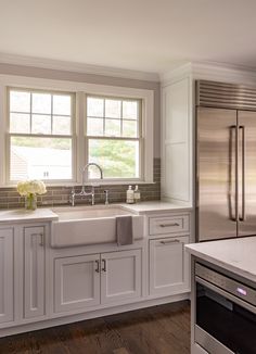 a clean kitchen with white cabinets and stainless steel appliances, including a double door refrigerator