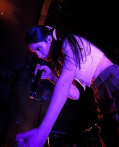 a young woman holding a microphone in her right hand and looking down at the ground