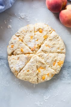 an uncooked peach scones on a table next to fresh peaches