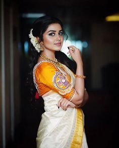 a beautiful woman in an orange and white sari posing for the camera with her hand on