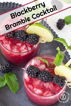 two glasses filled with fruit and garnish on top of a black plate