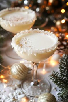 two glasses filled with drinks sitting on top of a table next to christmas decorations and lights