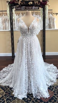 a white wedding dress on display in front of a storefront with flowers and lace