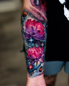 a person with a tattoo on their arm holding a cell phone in one hand and flowers in the other