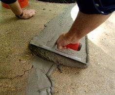 a person using a squirt to clean cement on the ground with a sponge