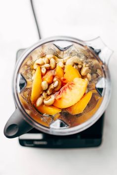 a blender filled with fruit and nuts on top of a white countertop,