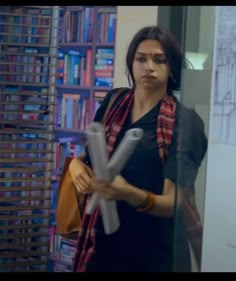 a woman standing in front of a bookshelf holding a large piece of paper