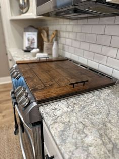 a kitchen with marble counter tops and stainless steel oven hoods, white subway backsplash