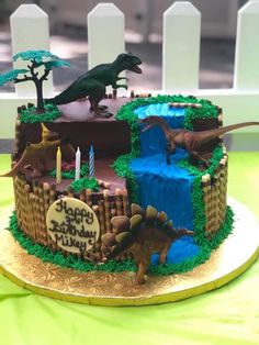 a birthday cake decorated with dinosaurs and trees