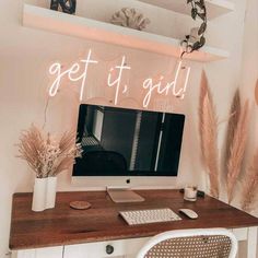 a desk with a computer on it and some plants in vases next to it