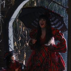 a woman in a red and black dress holding an umbrella