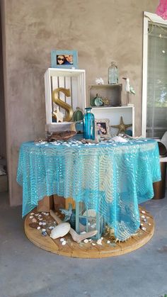 a blue table cloth on top of a wooden stand with shells and seashells