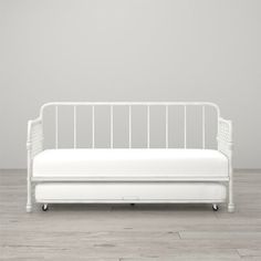 a white daybed sitting on top of a hard wood floor next to a wall