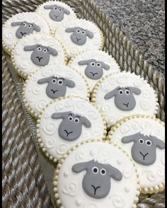 several decorated cookies in the shape of sheep on a table with gray and white icing