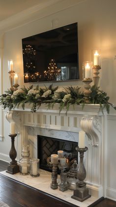 a mantel with candles and greenery on it