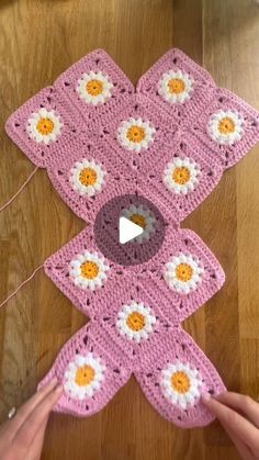 someone is crocheting flowers on a pink blanket