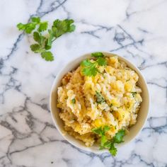 a white bowl filled with rice and cilantro on top of a marble counter