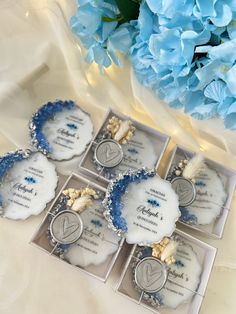 four blue and white wedding favors are in their boxes next to some hydrangeas