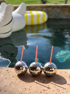 three silver balls sitting next to each other on top of a table near a pool