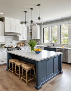 a large kitchen with white cabinets and blue island