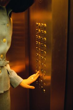 there is a doll that is standing in front of the elevator door and holding her hand out