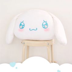 a white stuffed animal sitting on top of a wooden stool next to a cloud filled wall