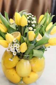 a glass vase filled with lemons and flowers