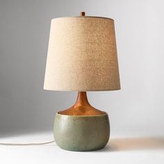 a table lamp with a beige shade on the base and a light bulb plugged in