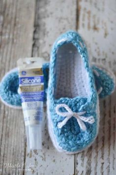 a pair of blue crocheted baby shoes next to a tube of toothpaste