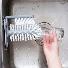 a hand is holding a brush over a sink