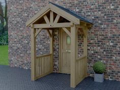 a wooden gazebo sitting next to a brick wall with a potted plant in it