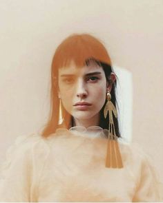 a woman with long hair wearing gold earrings