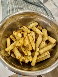 a metal bowl filled with french fries on top of a table