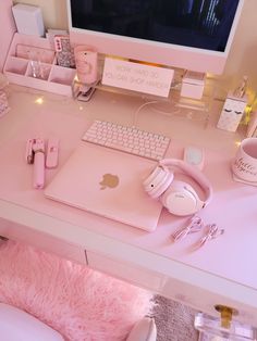 a pink desk with a computer and headphones on it, in front of a white chair