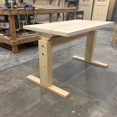 a wooden table sitting on top of a floor next to a workbench in a garage