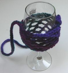 a crocheted wine glass holder with a purple handle