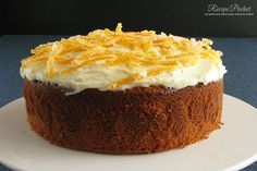 a close up of a cake on a plate with frosting and orange zest